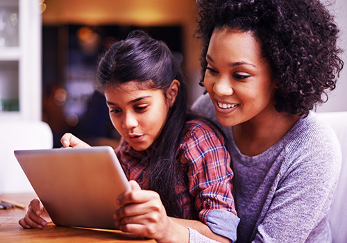 Mother doing homework on iPad with daughter