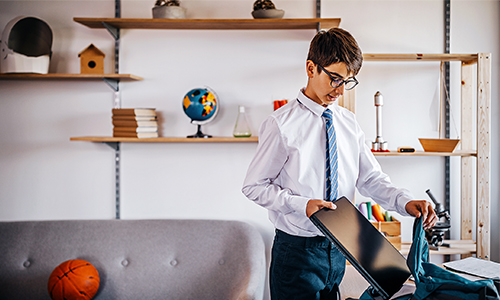 Male student packing mobile device into his bag