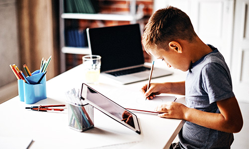 A school boy at home with a one to one device